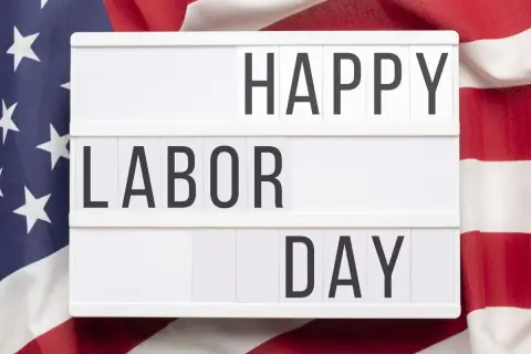 Cartel luminoso con "HAPPY LABOR DAY" sobre bandera de EE.UU. Celebrando el día del trabajador en inglés.