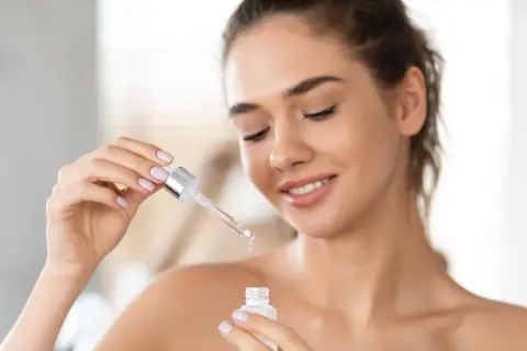 Une femme applique un sérum à la vitamine A rétinol pour une peau éclatante.
