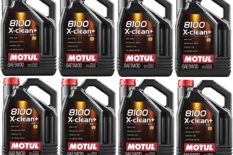 Cztery czarne kanistry oleju silnikowego Motul 8100 X-clean+ SAE 5W30 z czerwonymi nakrętkami.