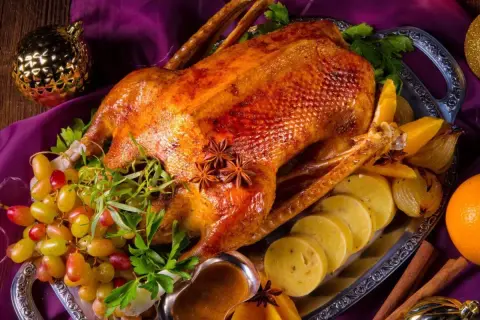 Eine goldbraune Gans auf dem Grill, garniert mit Trauben, Orangen und Sternanis. Perfekt für ein festliches Mahl.