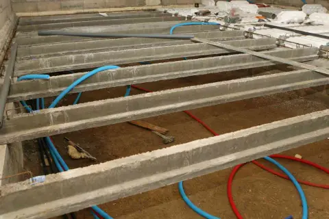Construction d'un vide sanitaire avec poutrelles béton et tuyaux bleus. Préparation pour comment ventiler un vide sanitaire.