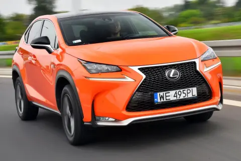 Pomarańczowy Lexus NX300h pędzi po drodze, jego dynamiczna sylwetka i nowoczesne linie przyciągają wzrok.