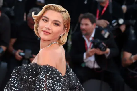Peinados melena corta boda: rubia con ondas suaves y un vestido negro brillante, lista para un evento especial.