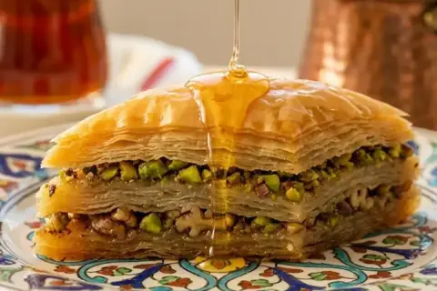Delizioso baklava ricetta con strati di pasta fillo, pistacchi e noci, inzuppato in sciroppo dorato.
