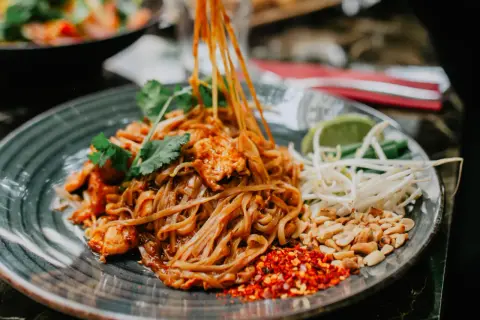 Pyszny pad thai z kurczakiem, orzeszkami, kiełkami i limonką. Tak jemy pad thai, dodając przyprawy do smaku.