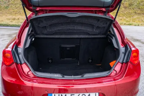 Bagażnik czerwonego Alfa Romeo Giulietta, gotowy na podróż.