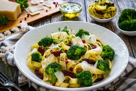Pyszny obiad z brokułem: tagliatelle z zielonymi różyczkami, suszonymi pomidorami i parmezanem.