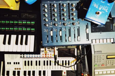 A musician's setup with keyboards, a mixer, and a blue "Time Space" pedal. This image shows how to clear sample data from a synthesizer.