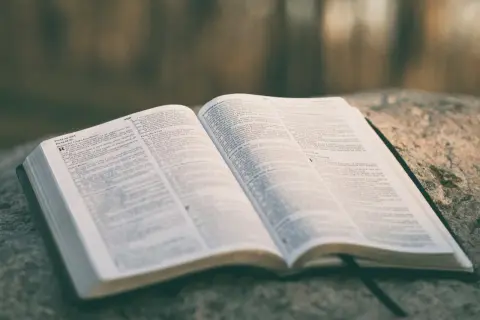 Otwarta księga Biblii na kamieniu, z widocznym tekstem. Wśród stron znajduje się psalm o miłości, który można odnaleźć w tym świętym tekście.