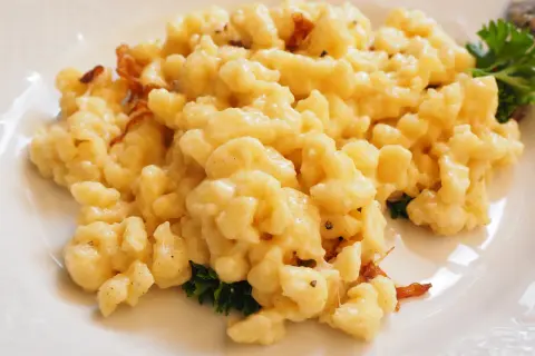 Gnocchetti di patate conditi con formaggio fuso e speck croccante, un classico dei primi piatti trentini.