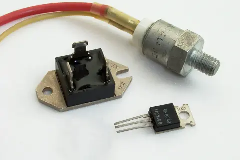 Trzy elementy elektroniczne: mostek prostowniczy, tranzystor TIC246D i metalowy element z gwintem, prawdopodobnie regulator napięcia.