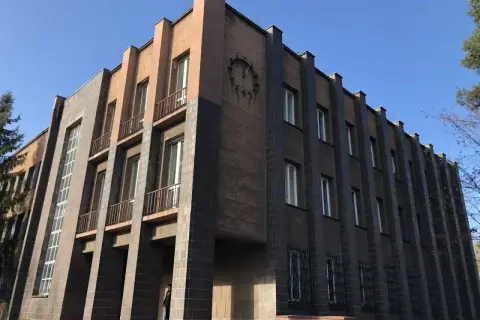 Monumentalny budynek z zegarem, przykład art deco w Polsce. Geometryczne formy, ciemna i jasna elewacja, wąskie okna.