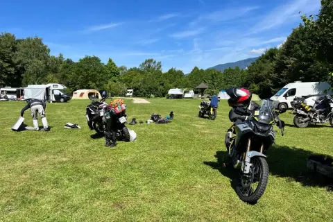 Motocykle zaparkowane na kempingu, w tle namioty i kampery.