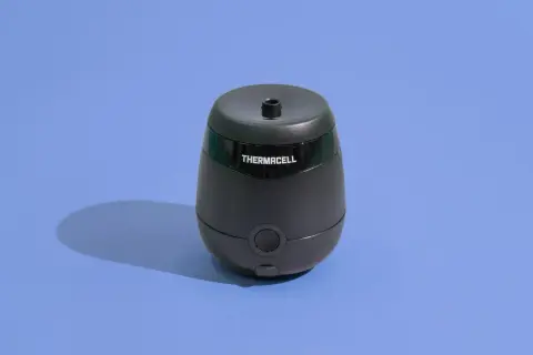 Czarny odstraszacz Thermacell na niebieskim tle. Zapewnia strefę wolną od kleszczy, chroniąc ludzi.