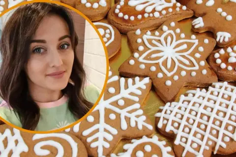 Ania gotuje pyszne pierniczki ozdobione białym lukrem. Widać jej uśmiechniętą twarz i świąteczne ciasteczka w kształcie gwiazdek i płatków śniegu.