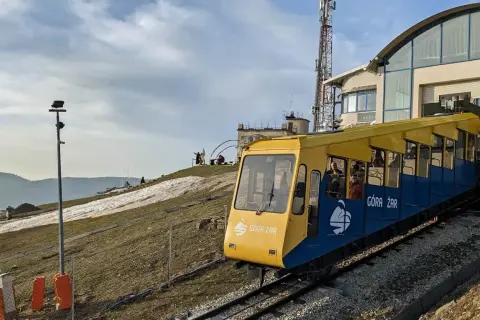 Kolejka linowo-terenowa Góra Żar wjeżdża na szczyt. Widok na trasę i budynek stacji.