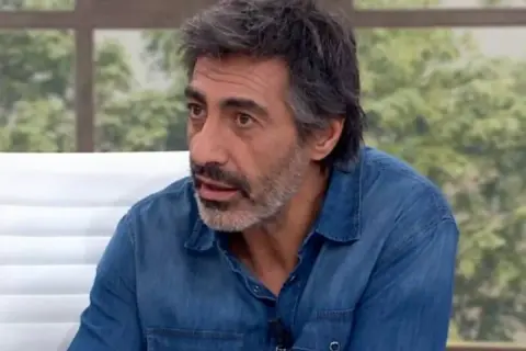 Juan del Val, con su característica barba y camisa vaquera, reflexiona en un plató de televisión.