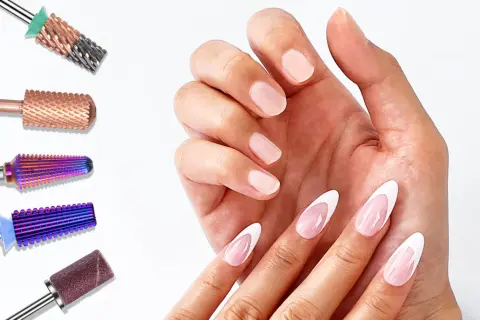 Różne frezy do paznokci, w tym idealny frez do ściągania żelu, obok dłoni z eleganckim french manicure.