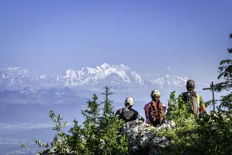 Trois randonneurs contemplent les sommets enneigés après une randonnée dans le Jura.