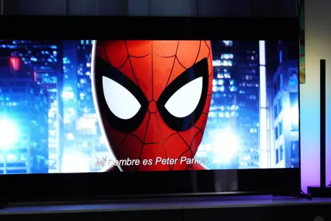 Spider-Man na ekranie telewizora, porównanie technologii QD OLED vs OLED. W tle nocne miasto.