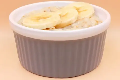 Pyszna owsianka z bananem w szarej miseczce, idealna na zdrowe śniadanie.