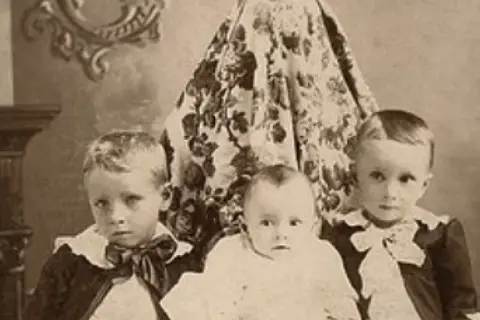 Trójka dzieci, w tym niemowlę, pozuje do portretu. Czy Isamu ma dzieci? Ta fotografia sugeruje, że tak, ma co najmniej trójkę.