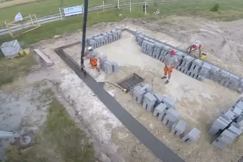 Budowa fundamentów: betonowanie i układanie bloczków przez robotników.
