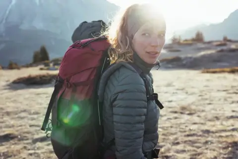 Kobieta z plecakiem w górach, gotowa na przygodę. To prawdziwy backpacking po polsku, z widokiem na majestatyczne szczyty.