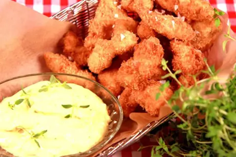 Korg med gyllene chicken nuggets, serverade med en krämig dipp och färska örter.