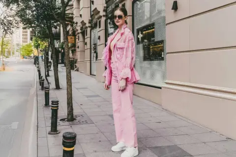Ein Model präsentiert, wie man **pinke Hose kombinieren** kann: mit einem passenden pinken Spitzen-Blazer und weißen Sneakern.