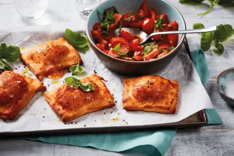 Goldbraune Teigtaschen, gefüllt und gebacken, zeigen, was man aus pizzateig machen kann. Dazu ein frischer Tomatensalat.