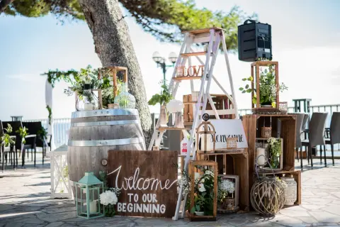 Décoration porte d'entrée pour mariage : un tonneau, une échelle décorée, des caisses en bois et des lanternes accueillent les invités.