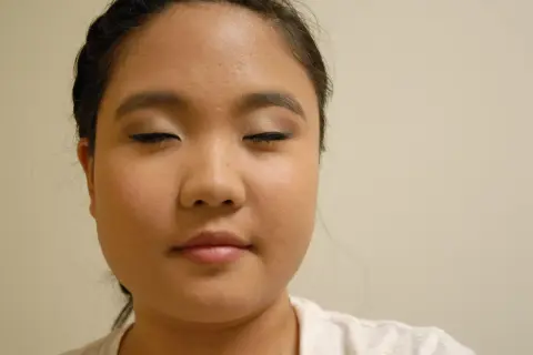 Primer plano de una mujer con los ojos cerrados y maquillaje en los párpados y delineador.