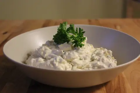 En skål med krämig tarator djej, toppad med färsk persilja.