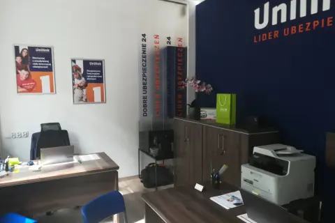 Biuro firmy ubezpieczeniowej Unilink z plakatami, drukarką i meblami.