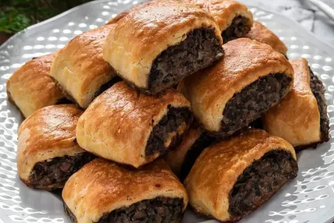 Złociste paszteciki z pieczarkami, ułożone na białej paterze, kuszą aromatem i chrupiącą skórką. Idealne na każdą okazję.