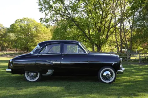 Svart Vauxhall Cresta parkerad på en gräsmatta med träd i bakgrunden.
