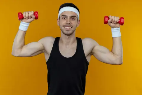 Ein Mann mit Stirnband und Schweißbändern macht Unterarmtraining mit roten Hanteln.