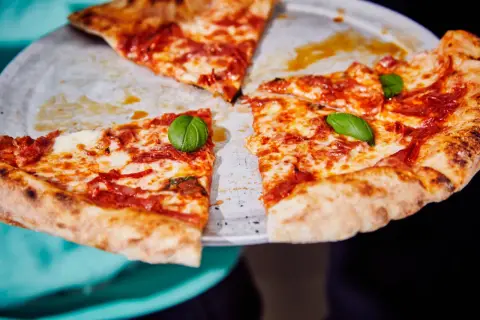 Une pizza diabola appétissante, avec sa croûte dorée, sa sauce tomate épicée et son fromage fondant, garnie de feuilles de basilic frais.