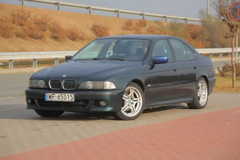 Ciemnozielone BMW E39 z polskimi tablicami WF 65015 stoi na parkingu.