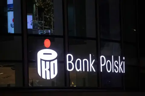 Świecący napis PKO Bank Polski. W tle choinka i odbicia. Inwestorzy liczą na dywidendę PKO BP.