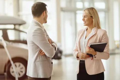 Ein Mann und eine Frau sprechen im Autohaus. Sie überlegen, ob sie ein Auto leasen oder kaufen sollen.