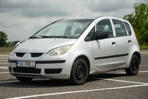Srebrny Mitsubishi Colt z tablicą rejestracyjną PGN 798LL stoi na parkingu.