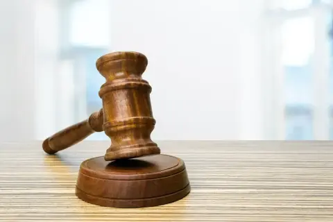 Drewniany młotek sędziowski na stole. Zastanawiasz się, ile czasu ma sąd na rozpatrzenie wniosku?