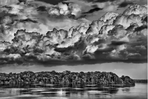 Dramatyczne chmury nad Amazonką, uchwycone przez Sebastiao Salgado. Potężna rzeka i bujna dżungla.