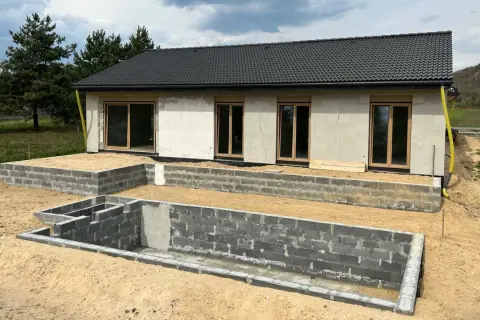 Budowa domu w 3 forma build. Fundamenty z bloczków betonowych, ściany z betonu komórkowego, dach pokryty dachówką.