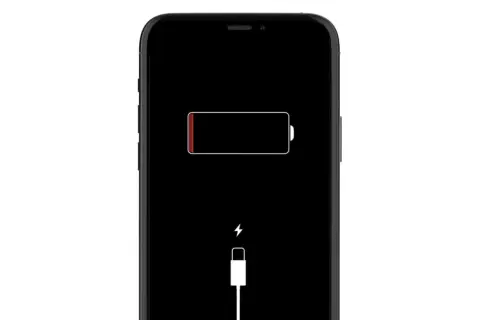 Czarny ekran iPhone'a z ikoną rozładowanej baterii i symbolem ładowania. iPhone nie ładuje się.