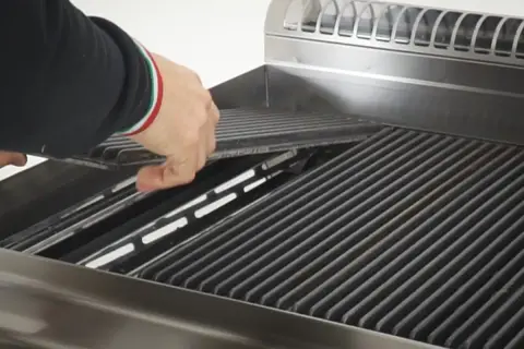 Mano che posiziona le pietre laviche nel barbecue a gas, pronte per una grigliata perfetta.