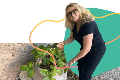Une femme souriante jardine, un exemple de loisirs pour jeunes retraités actifs et épanouis.