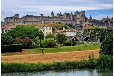 Majestatyczna twierdza Carcassonne góruje nad miastem, otoczona zielenią i rzeką.
